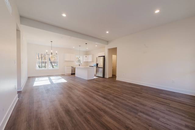 unfurnished living room with sink, a chandelier, and dark hardwood / wood-style floors