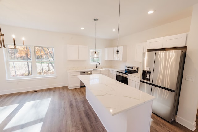 kitchen with plenty of natural light, a kitchen island, stainless steel appliances, and light hardwood / wood-style flooring