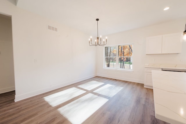 unfurnished dining area featuring light wood-type flooring and an inviting chandelier