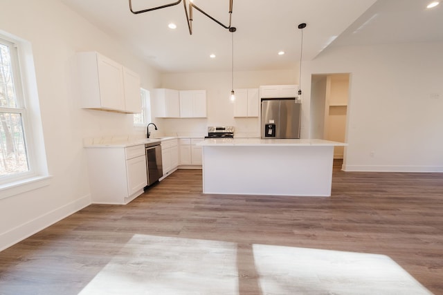 kitchen featuring appliances with stainless steel finishes, white cabinetry, a wealth of natural light, and a kitchen island