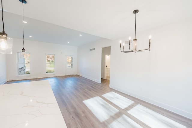 unfurnished dining area featuring a chandelier and light hardwood / wood-style flooring