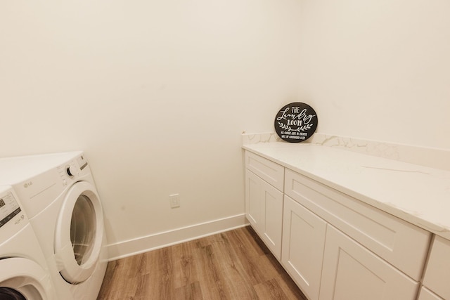 clothes washing area featuring light wood-type flooring, washing machine and dryer, and cabinets