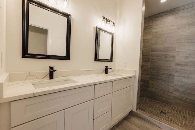 bathroom with tiled shower, vanity, and hardwood / wood-style flooring