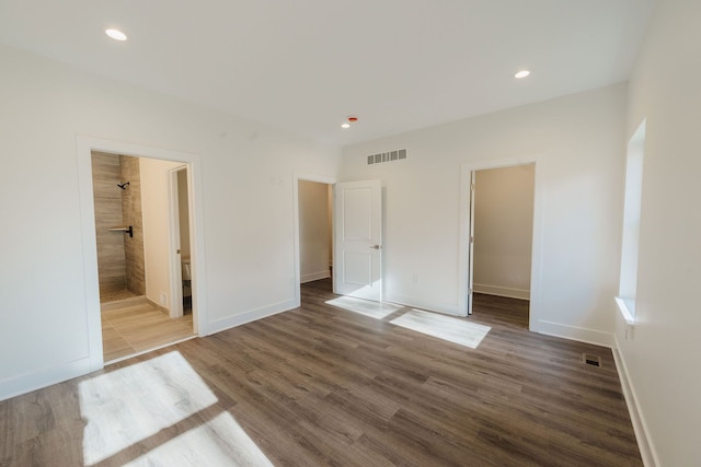 unfurnished bedroom with hardwood / wood-style floors, a closet, a walk in closet, and ensuite bath