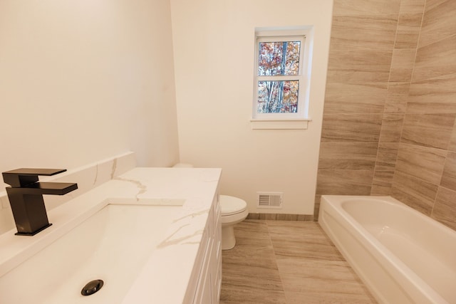 bathroom with a bathing tub, vanity, toilet, and tile patterned floors