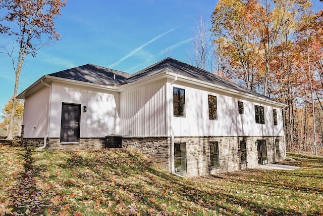 back of property featuring cooling unit and a lawn