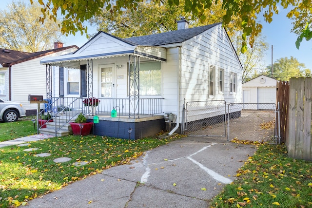 bungalow with a porch, an outbuilding, a front yard, and a garage