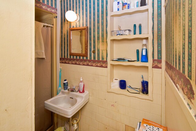 221 N 6th St, Niles, MI 49120 - bathroom with wallpapered walls, a sink, a wainscoted wall, a shower with shower curtain, and tile walls