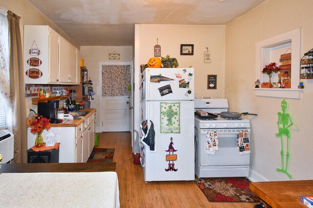 221 N 6th St, Niles, MI 49120 - kitchen featuring white appliances, a sink, light wood-style flooring, white cabinets, and backsplash