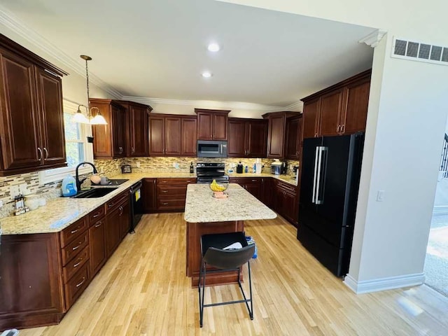 kitchen with black appliances, decorative light fixtures, a center island, and light hardwood / wood-style floors