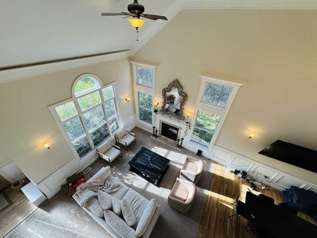 living room with ceiling fan, crown molding, high vaulted ceiling, and wood-type flooring