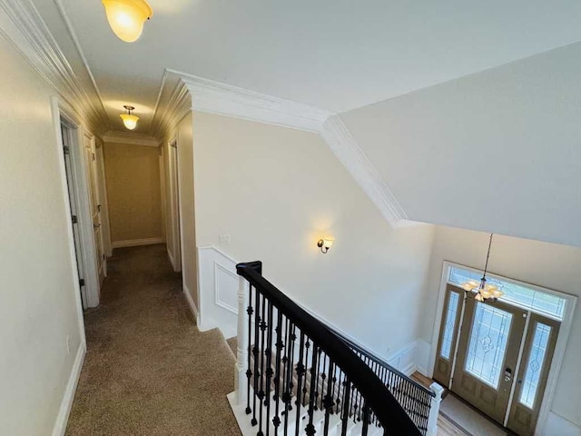 corridor featuring carpet flooring, an inviting chandelier, and ornamental molding