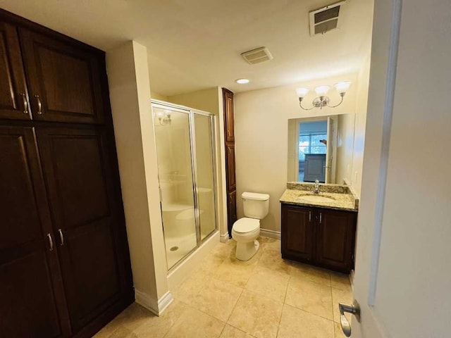 bathroom with tile patterned floors, a shower with door, vanity, and toilet