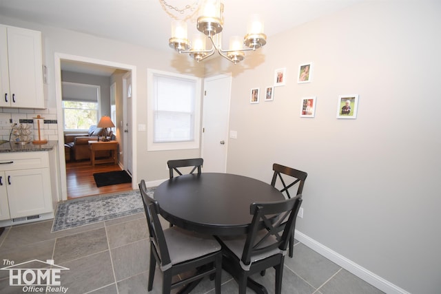 dining space with dark tile patterned floors and a notable chandelier