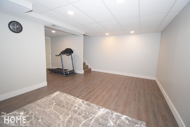 exercise room featuring a paneled ceiling and dark hardwood / wood-style flooring