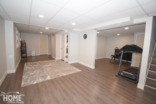 workout area with a drop ceiling and dark wood-type flooring