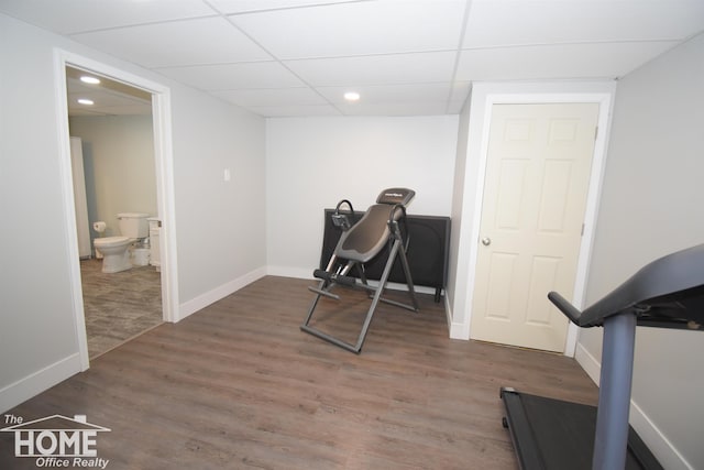 exercise room with dark hardwood / wood-style flooring and a drop ceiling