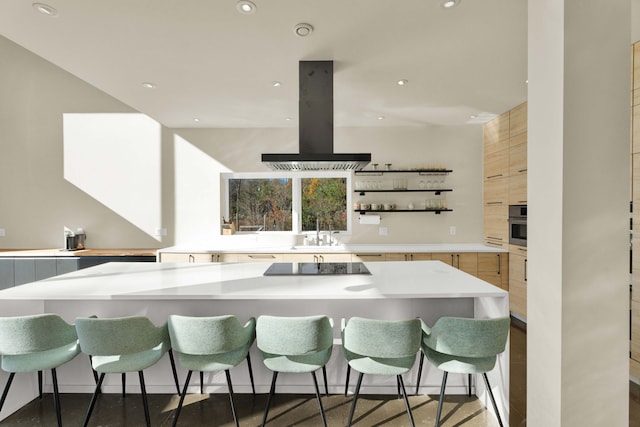 kitchen with island range hood, a breakfast bar, stainless steel oven, and black electric stovetop