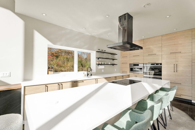 kitchen featuring sink, black electric stovetop, a kitchen bar, island range hood, and light brown cabinetry