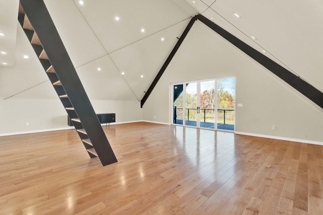 unfurnished living room with light wood-type flooring and high vaulted ceiling