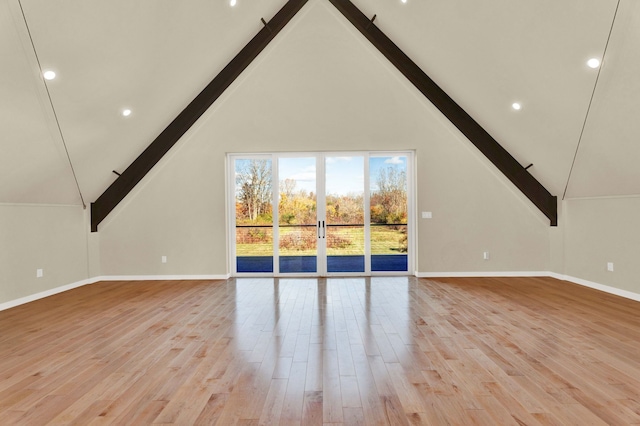 unfurnished living room featuring beam ceiling, high vaulted ceiling, and light hardwood / wood-style flooring