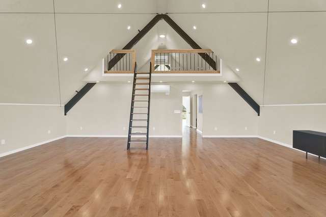 unfurnished living room with a wall unit AC, beamed ceiling, high vaulted ceiling, and hardwood / wood-style flooring