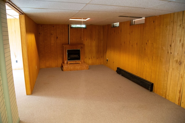 basement with a paneled ceiling, carpet floors, and wooden walls