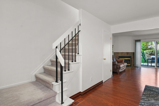 staircase with a fireplace and hardwood / wood-style floors