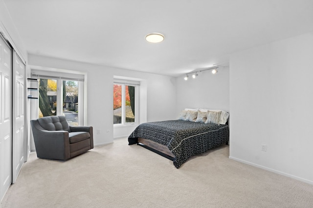 bedroom featuring light carpet and rail lighting