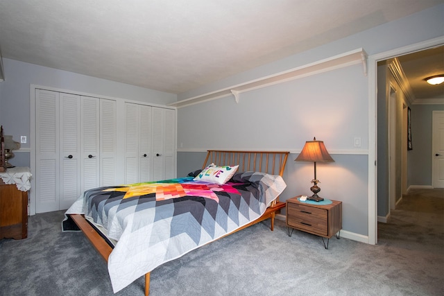 carpeted bedroom with ornamental molding and two closets