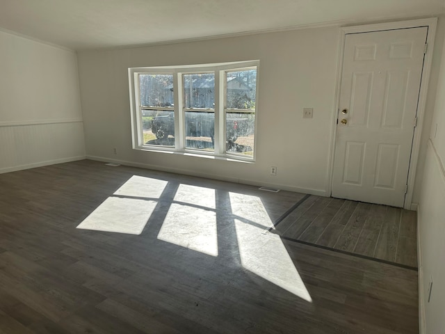 spare room with crown molding and dark wood-type flooring