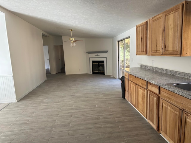 kitchen with ceiling fan, sink, light hardwood / wood-style floors, and a textured ceiling