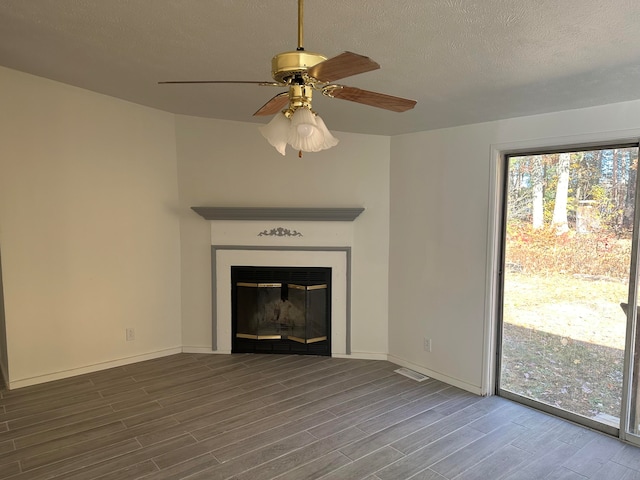 unfurnished living room featuring ceiling fan, a textured ceiling, and hardwood / wood-style flooring