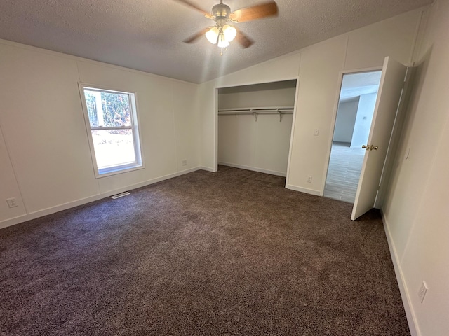 unfurnished bedroom with ceiling fan, dark carpet, a textured ceiling, and vaulted ceiling