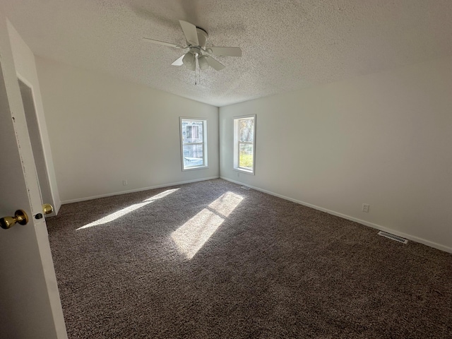 spare room featuring ceiling fan, dark carpet, and a textured ceiling