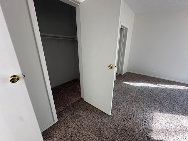 unfurnished bedroom featuring dark colored carpet and a closet