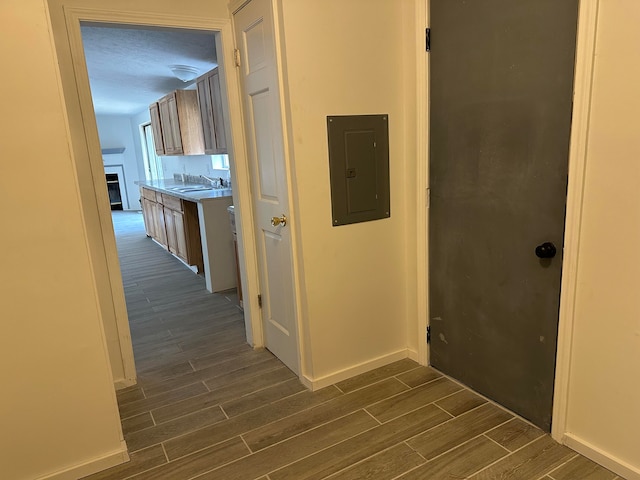 hallway featuring a textured ceiling, sink, dark wood-type flooring, and electric panel