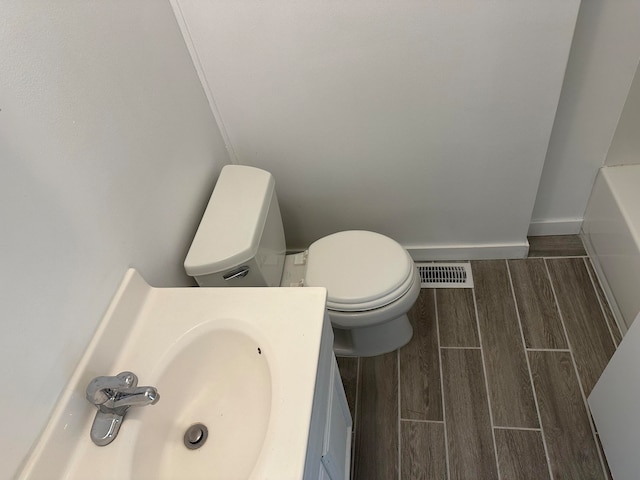 bathroom with wood-type flooring, vanity, and toilet