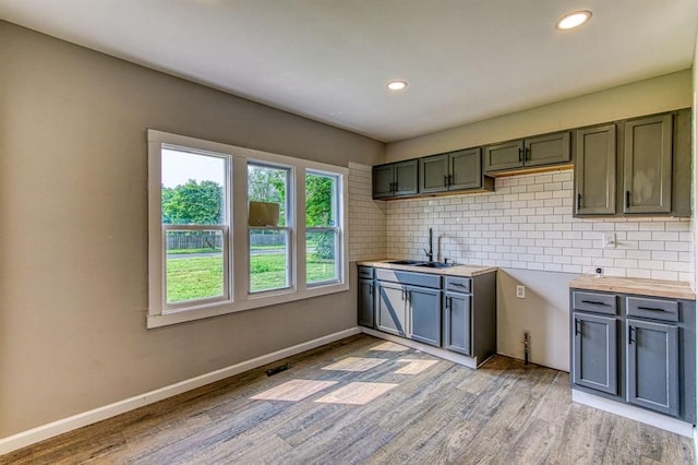 kitchen featuring decorative backsplash, sink, and light hardwood / wood-style flooring