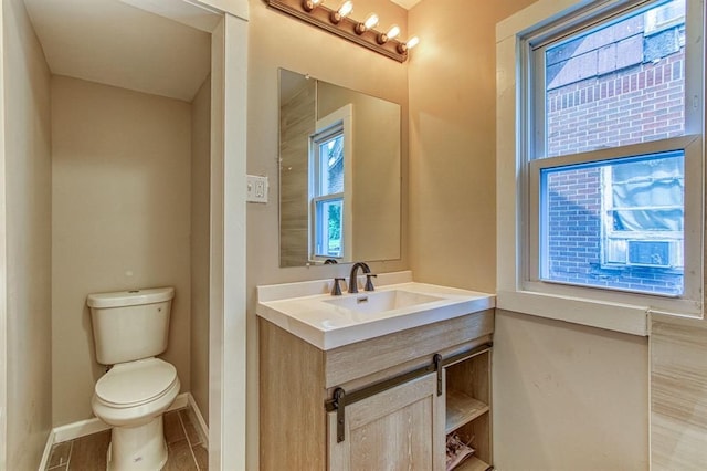 bathroom featuring tile patterned flooring, vanity, toilet, and a healthy amount of sunlight