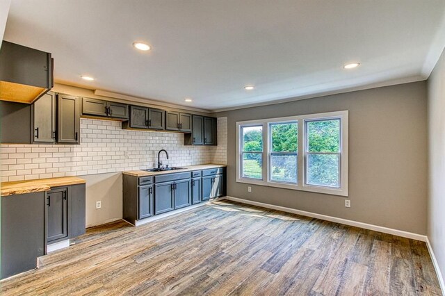 kitchen with sink, wood counters, light hardwood / wood-style flooring, gray cabinets, and decorative backsplash