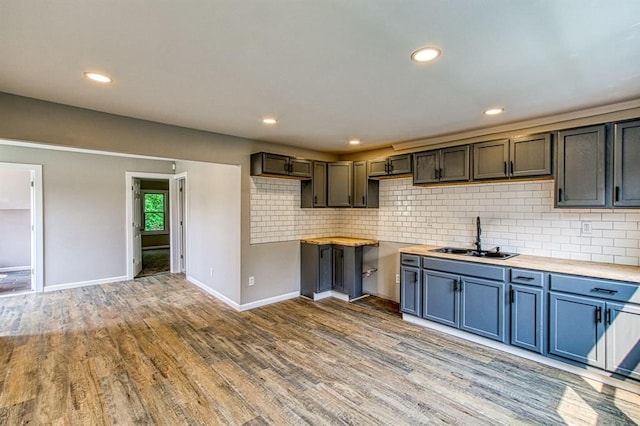 kitchen with tasteful backsplash, wood counters, sink, and light hardwood / wood-style flooring