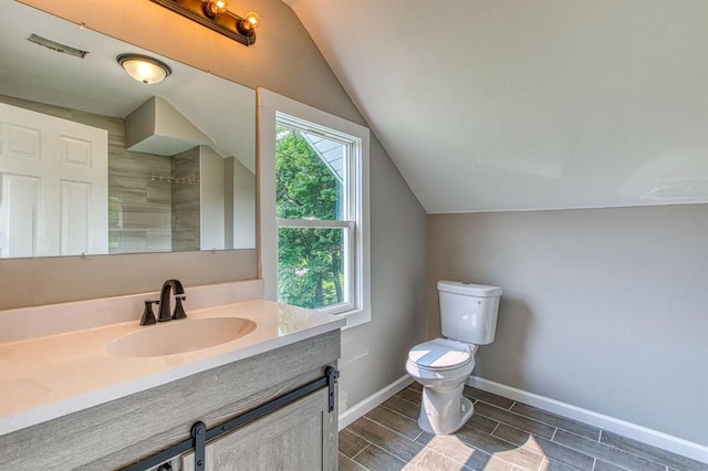 bathroom featuring toilet, vanity, and vaulted ceiling