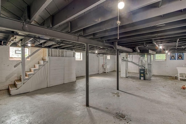 basement with brick wall, heating unit, and sink