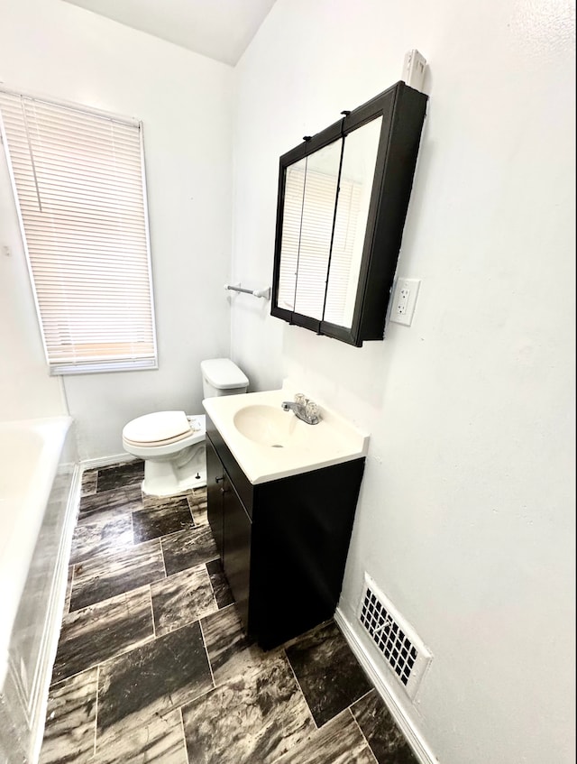 bathroom featuring a bath, vanity, and toilet