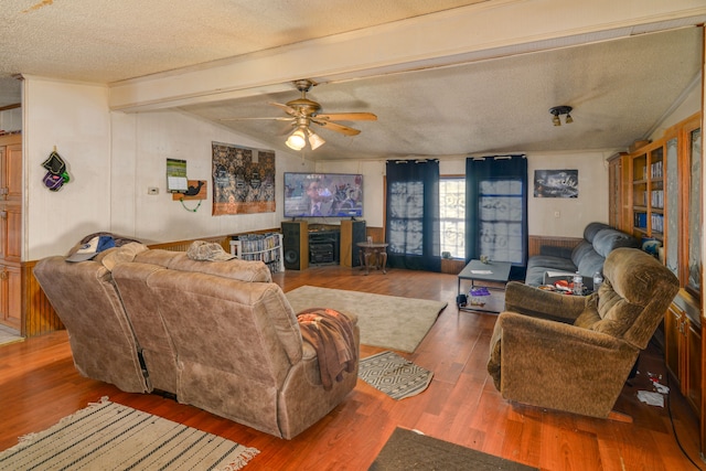 living room with a textured ceiling, vaulted ceiling with beams, ceiling fan, and dark wood-type flooring