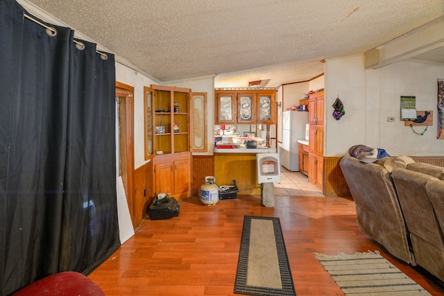 kitchen featuring white refrigerator, crown molding, light hardwood / wood-style floors, a textured ceiling, and vaulted ceiling