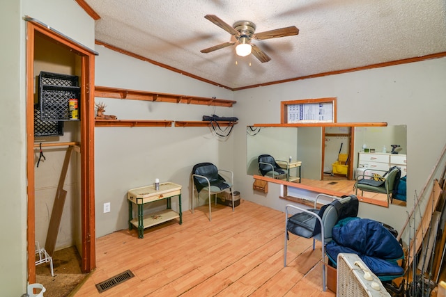 interior space featuring lofted ceiling, a textured ceiling, light hardwood / wood-style flooring, and crown molding