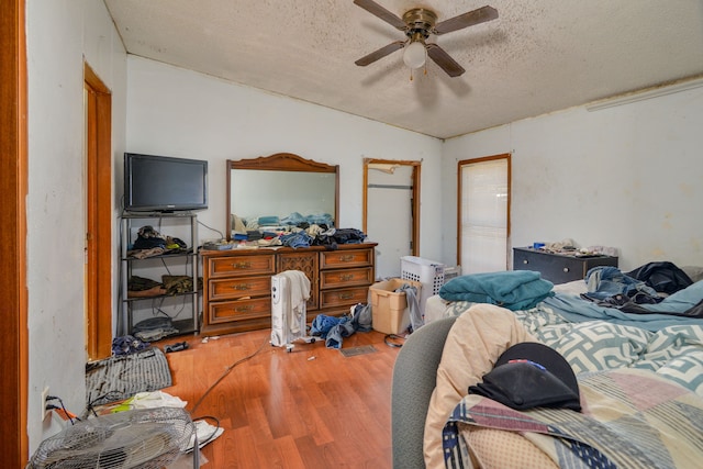 bedroom with a textured ceiling, hardwood / wood-style flooring, and ceiling fan