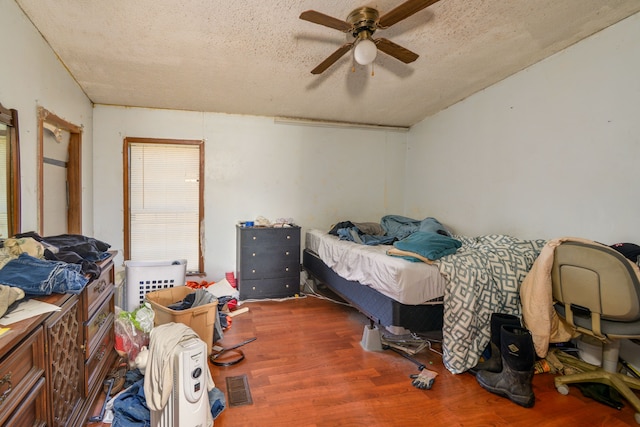 bedroom featuring ceiling fan, dark hardwood / wood-style flooring, and a textured ceiling